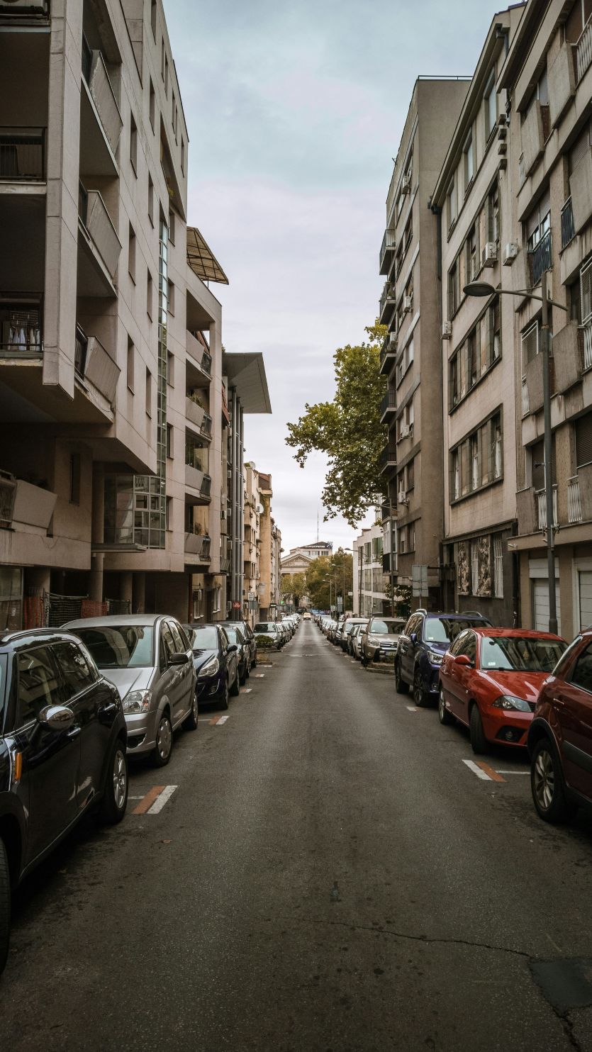 Stambena ulica sa vozilima parkiranim ispred ulaza u zgradu